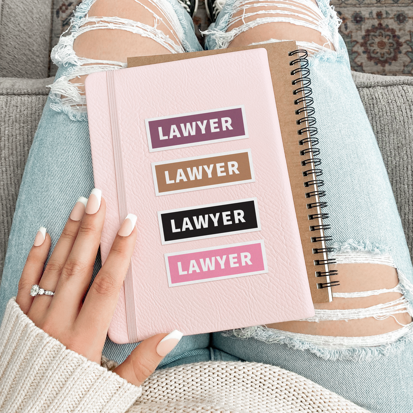 Person holding a pink notebook with 'Lawyer' text on a patterned rug.