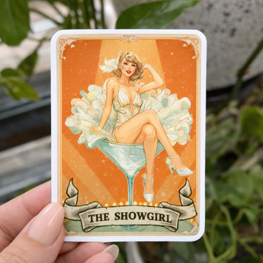 Card featuring 'The Showgirl' design held by a hand with plants in the background