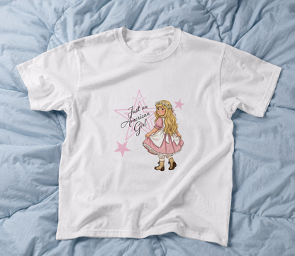 White coquette graphic tee with American girl inspired doll illustration on blue comforter