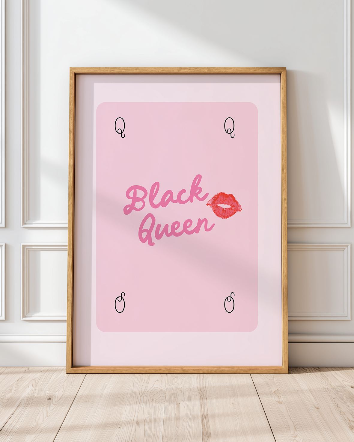 Black Queen pink printable wall art in wood frame leaning against paneled wall