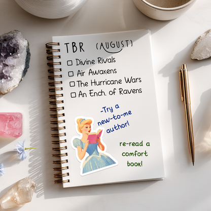 Notebook with TBR list, mug, flowers, and crystals on a light surface