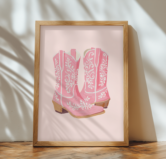 Framed artwork painting of pink cowboy boots on a light background. wood flooring