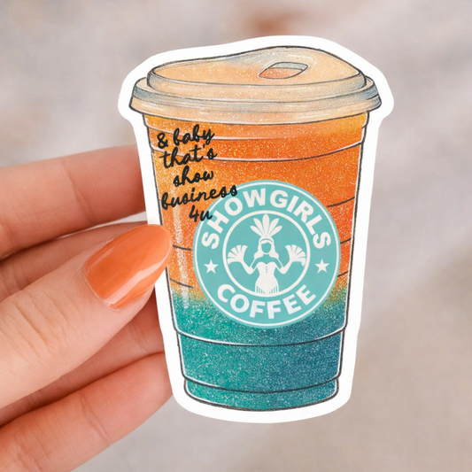 Sticker of a coffee cup with 'Showgirls Coffee' branding held by a hand.
