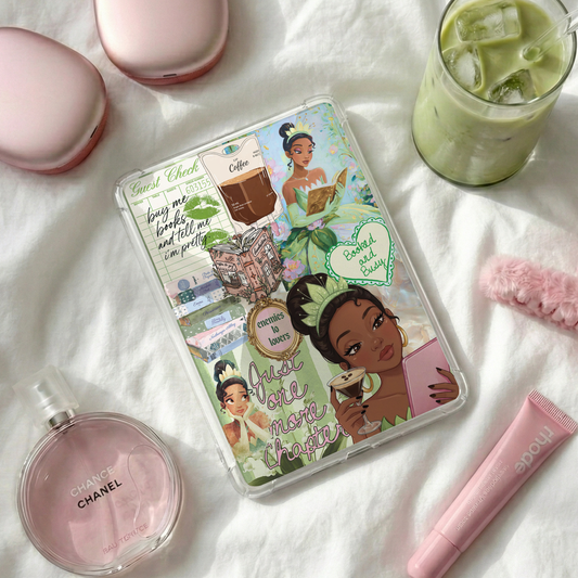 A clear hard-shell KINDLE case with colorful cartoon TIANA illustrations and text, styled on white fabric with pink accessories and a drink nearby.